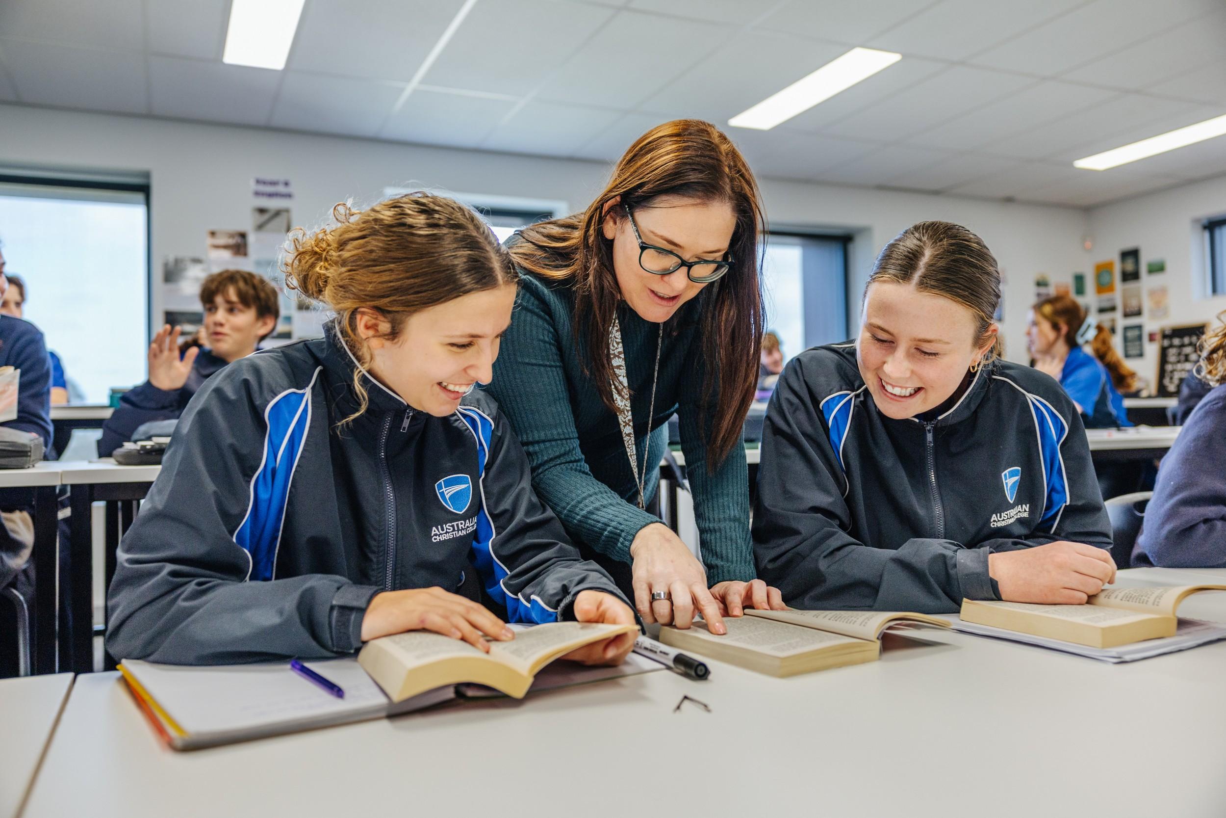 Teacher working with secondary students reading together in an Albany classroom