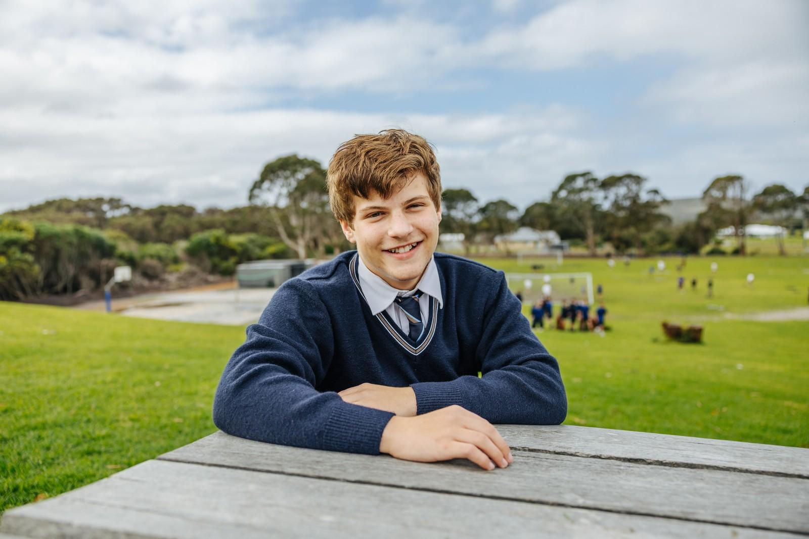Secondary boy in ACC Southlands formal uniform relaxing outdoors on school grounds