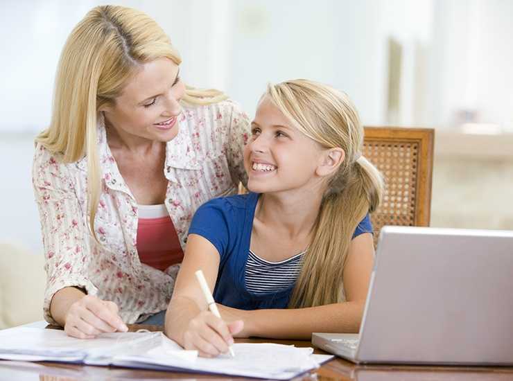 Smiling other and daughter completing distacne education lesson on laptop