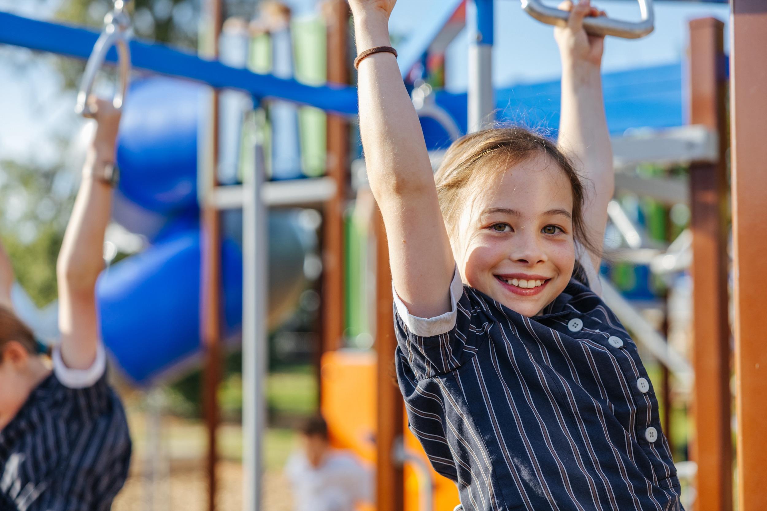 Smiling student on playground equipment at ACC Swan Hill, inviting families to book a tour and experience the school