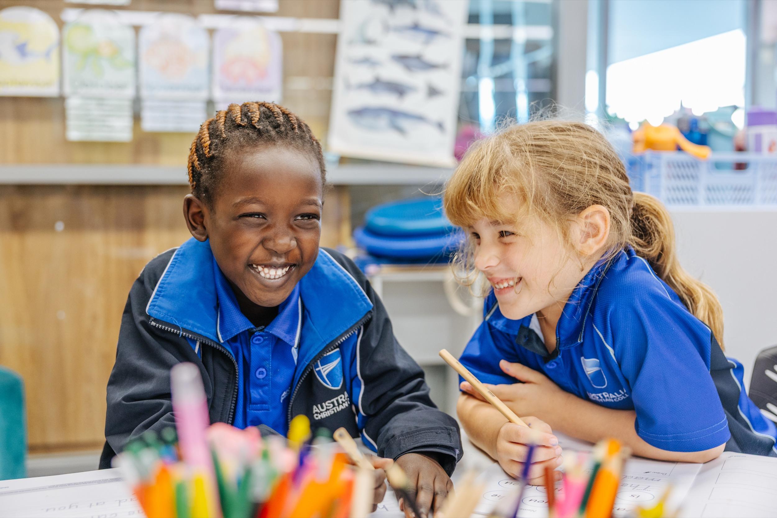 Two students at ACC Swan Hill smile and engage with each other while working on a creative project