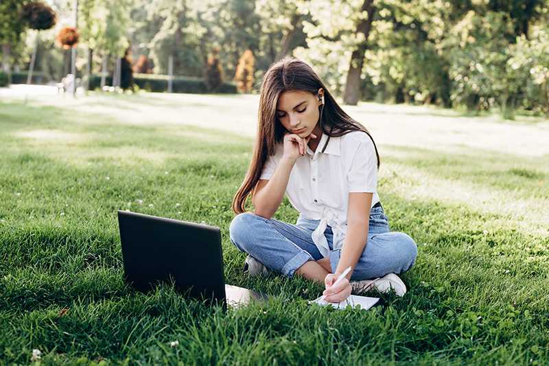High School aged Victorian student studying on laptop outside