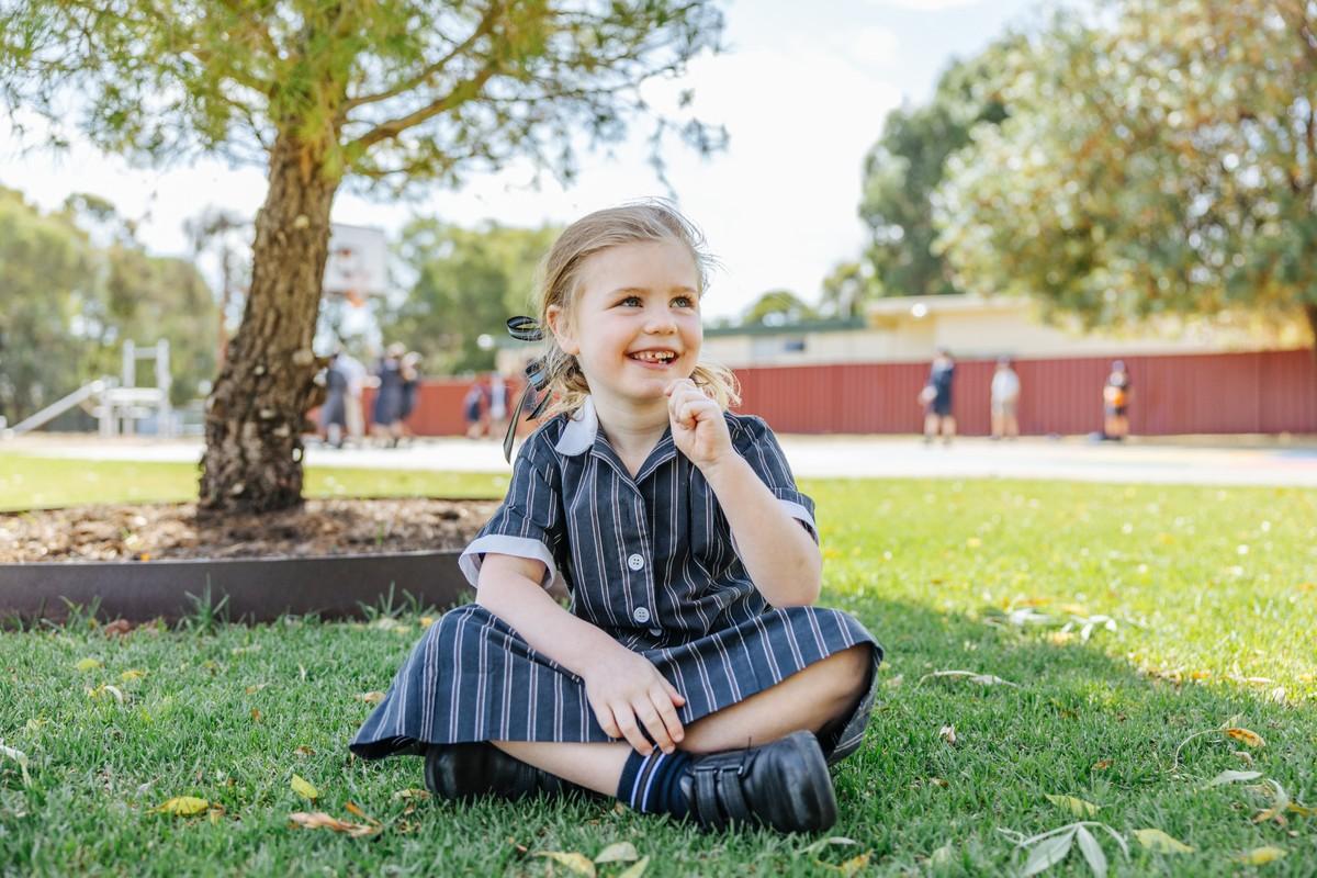 Primary student sitting on school grounds in ACC uniform